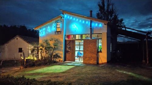 a house with blue lights on the side of it at Cabañas & Glamping De Ruana Por Boyacá in Paipa