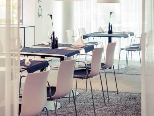 a dining room with tables and chairs with vases on them at Congress Hotel Mercure Nürnberg an der Messe in Nürnberg
