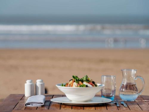 a bowl of food on a table near the beach at Le Médina Essaouira Thalassa Sea & Spa - MGallery Collection in Essaouira