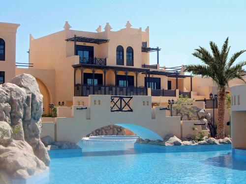 a house with a swimming pool in front of a house at Novotel Bahrain Al Dana Resort in Manama