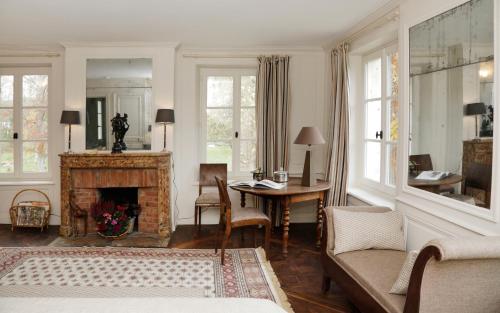 a living room with a fireplace and a table at Domaine du Plessis in Le Plessis-Luzarches