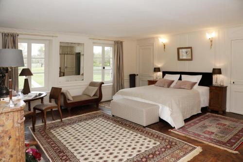 a bedroom with a white bed and a table and chairs at Domaine du Plessis in Le Plessis-Luzarches