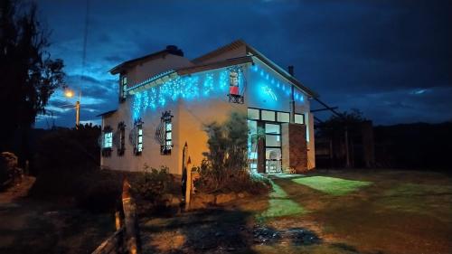 a house lit up at night with blue lights at Cabañas & Glamping De Ruana Por Boyacá in Paipa