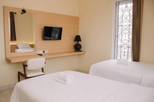 a bedroom with two beds and a mirror and a chair at Merlin Hotel in Maumere