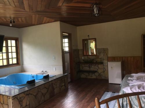 ein Bad mit einer blauen Badewanne in einem Zimmer in der Unterkunft Pousada Algama in Visconde De Maua