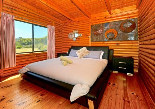 a bedroom with a bed in a wooden room at Cloudy Bay Cabin in South Bruny