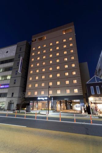 a tall building with windows on a street at night at Dormy Inn Mito in Mito