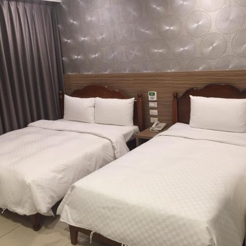 two beds in a hotel room with white sheets at Kousin Hotel in Kaohsiung
