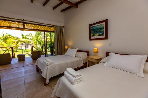 two beds in a hotel room with a window at Hotel Punta Camarón Bungalows & Suites in Zorritos