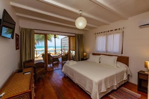 a bedroom with a bed and a view of the ocean at Hotel Punta Camarón Bungalows & Suites in Zorritos