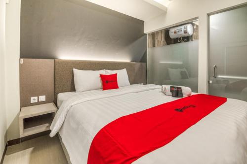 a bedroom with a red blanket on a bed at RedDoorz Plus near Akademi Kepolisian Semarang 3 in Candi