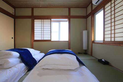 two beds in a room with two windows at Tiz wan 津名あわじ in Awaji