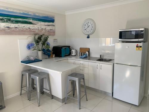 
a kitchen with a refrigerator, microwave and a table at Lazy Dayz Shellharbour in Shellharbour
