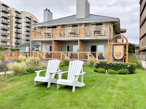 two white chairs sitting in the grass in front of a house at Inn at the Prom Oceanfront in Seaside