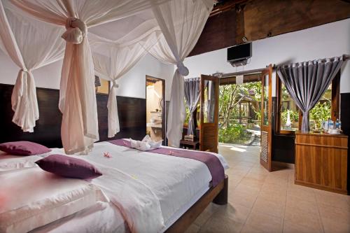 a bedroom with a large bed with mosquito nets at The Tanis Beach Resort Nusa Lembongan in Nusa Lembongan