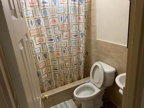 a bathroom with a toilet and a shower curtain at Casa De Pedro- Entire Villa in Mangilao
