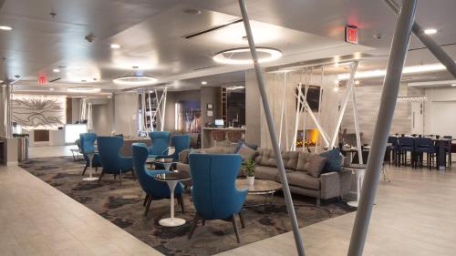 a waiting room with blue chairs and tables at Hotel Indigo Harrisburg - Hershey by IHG in Harrisburg