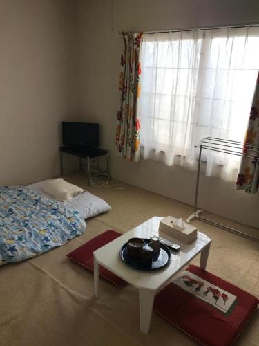 sala de estar con mesa, cama y ventana en STAY Akeboshi Kan en Hakodate