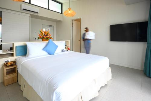 a bedroom with a large white bed and a tv at Loloata Island Resort in Loloata Island