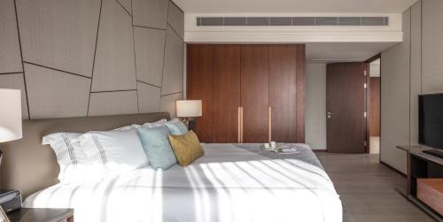 a bedroom with a large white bed and a television at Fraser Suites Dalian in Dalian