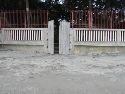 a pair of white fences with red gates at Felipa Beach and Guesthouse - Newly Renovated Airconditioned Guest Rooms in Dumaguete