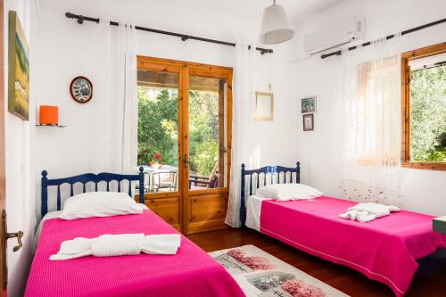 two beds in a room with a window at Katoussa in Paleokastritsa