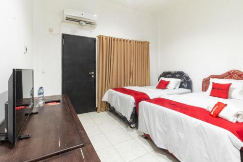 a hotel room with two beds and a television at RedDoorz near Bahu Mall Manado in Malalayang