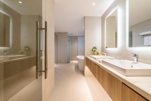 a bathroom with two sinks and a toilet and mirrors at Hanoi Hotel in Hanoi