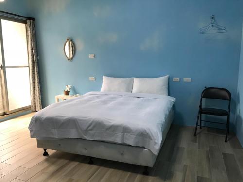 a blue bedroom with a bed and a chair at JOY Homestay in Shoufeng