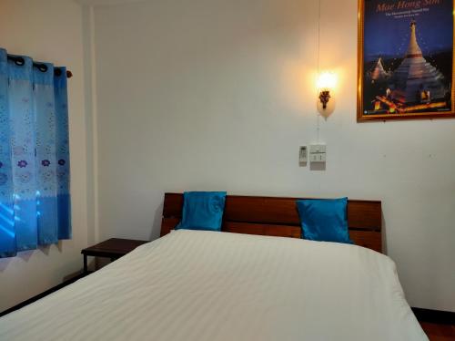 een slaapkamer met een wit bed met blauwe kussens bij Boondee House in Mae Hong Son