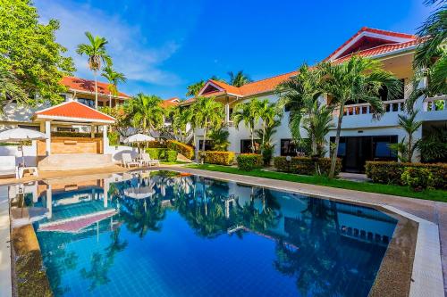 a swimming pool in front of a house with palm trees at Phuket Riviera Villas Hotel in Nai Harn Beach