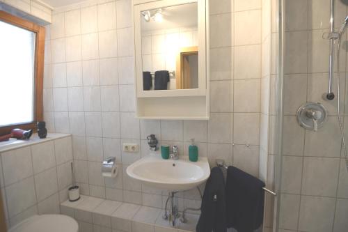 ein weißes Badezimmer mit Waschbecken und Dusche in der Unterkunft Hindenburg str Apartments in Garmisch-Partenkirchen
