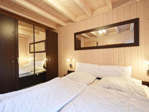 a bedroom with a large white bed and a mirror at Ferienhaus Ostseeblick 236 in Baabe