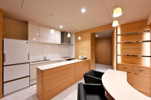 
a kitchen with a sink, a refrigerator, and a table at Oriental Suites Airport Osaka Rinku in Izumi-Sano
