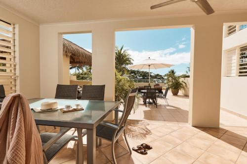 a dining room with a table and chairs and a patio at Sea Change Beachfront Apartments in Trinity Beach