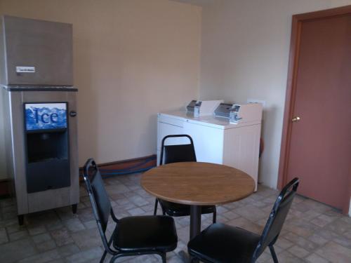 een kleine kamer met een tafel en stoelen en een koelkast bij High Chaparral Inn in Rocky Ford