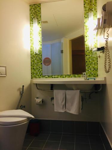 a bathroom with a toilet and a sink and a mirror at ibis Vientiane Nam Phu in Vientiane