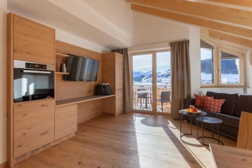 a living room with a couch and a television and a table at Apart-Hotel Dreisonnenhof in Fiss