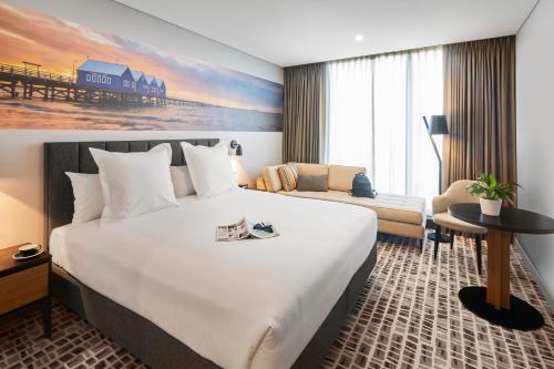 a hotel room with a large bed and a couch at Novotel Perth Murray Street in Perth