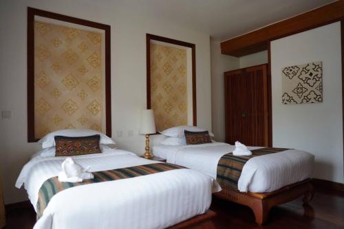 two beds in a hotel room with white sheets at Le Palais Juliana in Luang Prabang