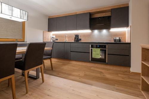 a kitchen with black cabinets and a table and chairs at Apartment Haus Schönwies in Alpbach