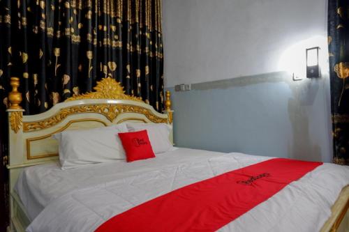 a bedroom with a bed with a red and gold headboard at RedDoorz @ Wangi-Wangi Island Wakatobi in Mandati