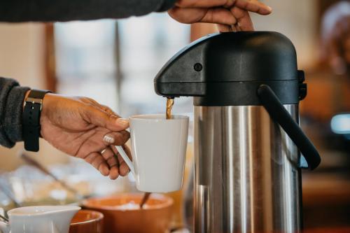 a person is pouring coffee into a coffee machine at The Village Lodge in Stormsrivier