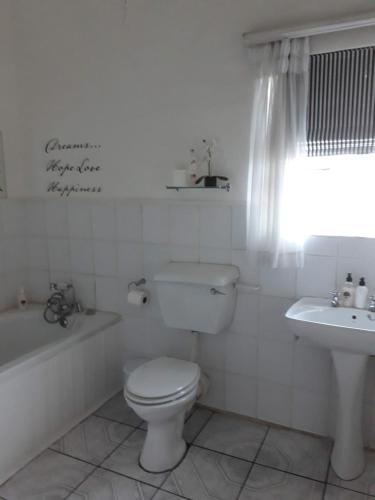 a white bathroom with a toilet and a sink at The Lighthouse Guesthouse in Colesberg