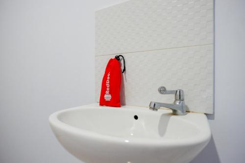 a white sink with a red item on top of it at RedDoorz @ Hotel Bravo Pantai Kamali Bau Bau in Baubau