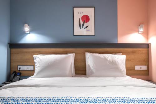 a bed with white sheets and a wooden headboard at Vera Hills Boutique Hotel in Tbilisi City
