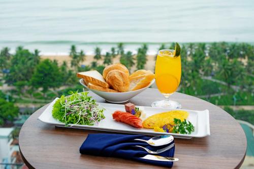 a table with a plate of food and a glass of orange juice at Seana Hotel in Nha Trang