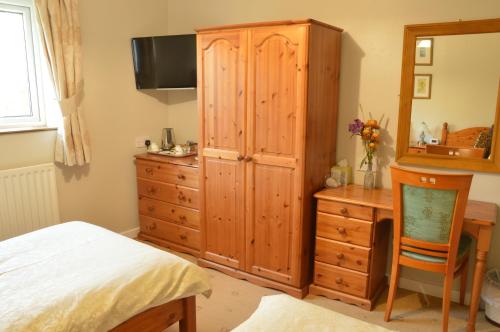 Un dormitorio con un gran armario de madera y un escritorio. en Bryn Hebog, en Carmarthen