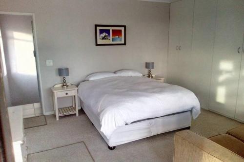 a bedroom with a large white bed and two tables at Somerset-West, Heldervue in Cape Town