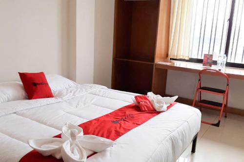 a room with two beds and a chair and a window at RedDoorz Plus @ Bitung City Center in Bitung